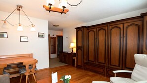 A spacious living room with a wooden dining table, a sofa, and a large cabinet. - Alpenhof by Interhome (Saas-Fee)