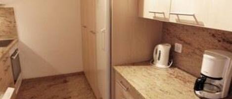 Een koelkast, een vaatwasser, kookgerei, borden en bestek