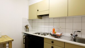 Eine kompakte Küche mit beigen Schränken, einer weißen Arbeitsplatte, einem Geschirrspüler und einem Spülbecken mit Armatur.