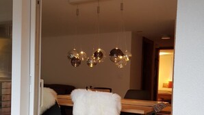 En matplats med ett träbord, svarta stolar med vita fällar och en taklampa.