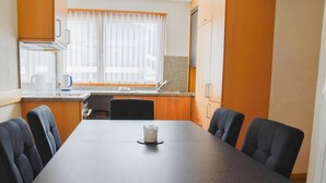A modern kitchen with a dining table, chairs, and a window with curtains. - Apartment Heidi by Interhome (Saas-Fee)