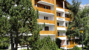 A multi-story hotel with balconies, surrounded by trees and a clear sky. - Apartment Apollo by Interhome (Saas-Fee)