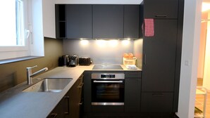 A compact kitchen with a built-in oven, a sink, and a coffee maker. - Apartment Apollo by Interhome (Saas-Fee)