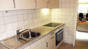 A modern kitchen with a double sink, stainless steel faucet, and a built-in oven. - Cristal by Interhome (Saas-Fee)