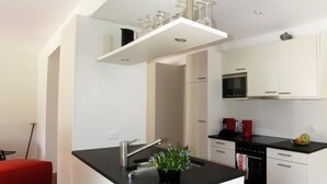 A compact kitchen with white cabinets, a black countertop, a built-in oven, and a microwave.