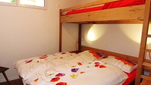 A bunk bed with a wooden frame and a single bed below.