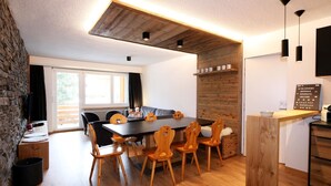 Uma área de refeições moderna com uma mesa e cadeiras de madeira, uma parede de pedra e uma janela grande.