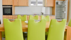 A compact kitchen with wooden cabinets, a built-in oven, and a refrigerator. There is a dining table with four chairs. - Apartment Heidi by Interhome (Saas-Fee)