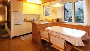 A compact kitchen with wooden cabinets, a central island, and a dining area with a table and chairs.