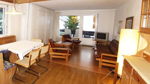 A cozy living room with wooden furniture, a TV, and a dining area with a table and chairs.