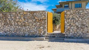 A stone wall with a yellow gate leading to a building with a tiled roof. - Marequì by Interhome (San Vincenzo)