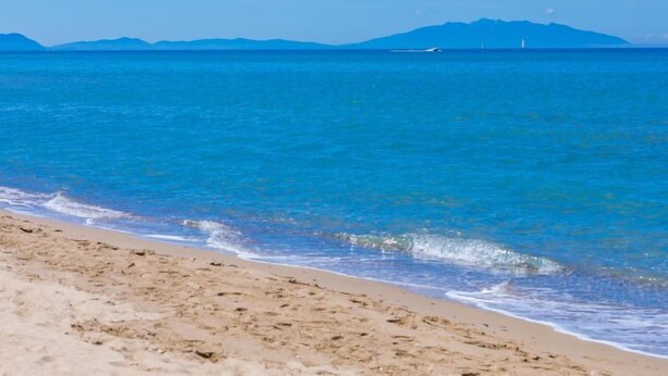 A beach with clear blue water and a distant mountain range. - Marequì by Interhome (San Vincenzo)