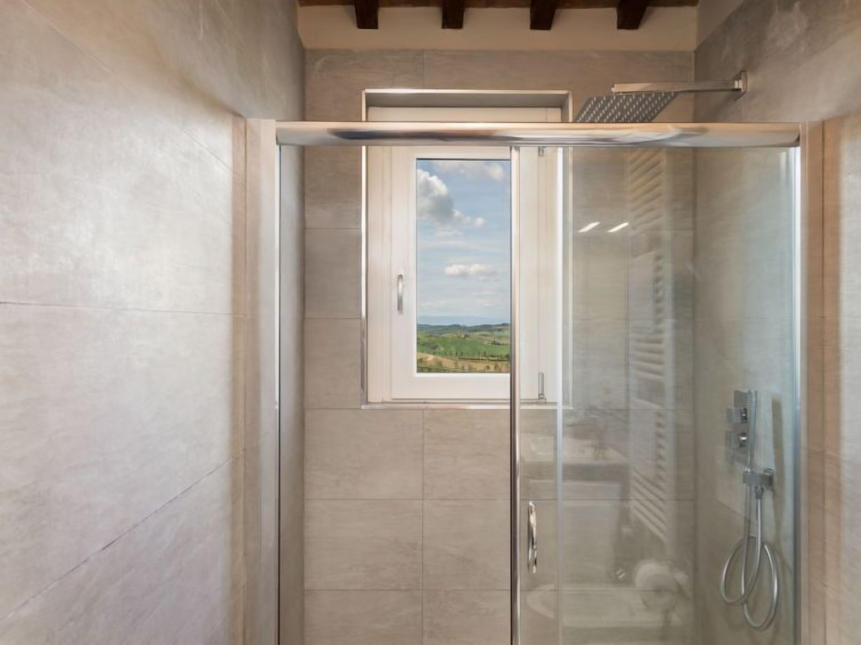 A glass-enclosed shower with a view of a landscape.