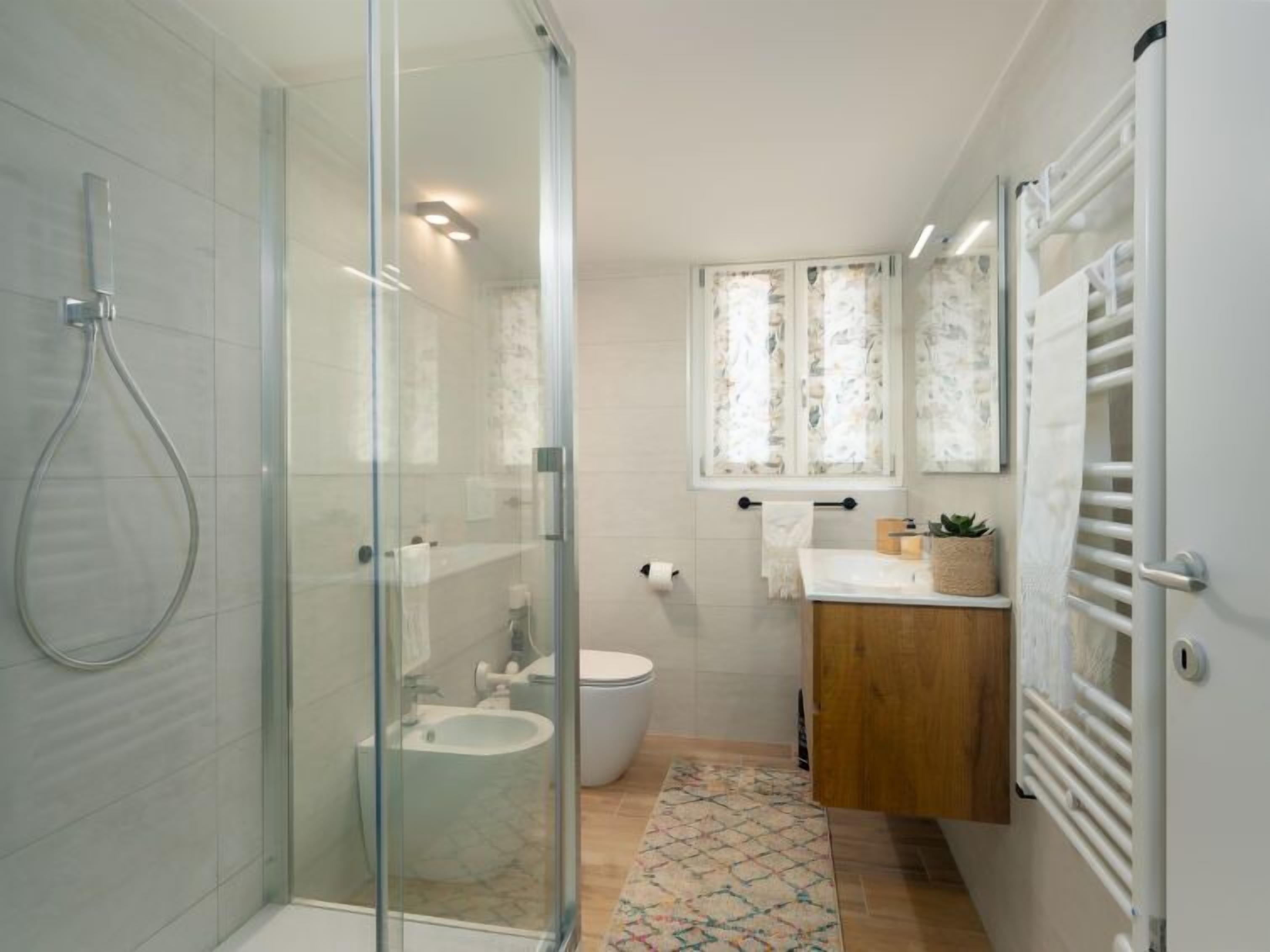 A modern bathroom with a glass shower enclosure, a toilet, and a sink.