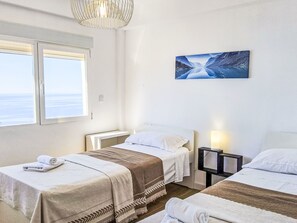 Une chambre dâhĂŽtel avec deux lits, une grande fenĂȘtre, un tableau et une lampe de chevet.