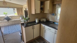 Una cocina pequeña con armarios de madera, una encimera y una ventana.