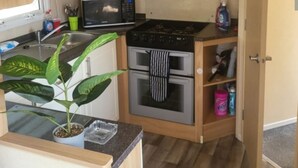 Cocina compacta con gabinetes de madera, microondas, estufa y pileta.