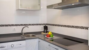 A modern kitchen with a built-in dishwasher, a stainless steel sink, and a microwave. - Abanicos by Interhome (Peñiscola)