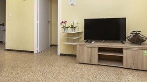 Een hotellobby met een houten tv-meubel, een klok en een groen vluchtroutebord.