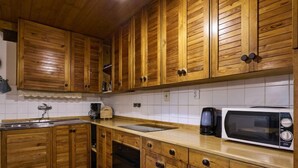 Een keuken met houten kastjes, een roestvrijstalen spoelbak, een magnetron en een koffiezetapparaat.