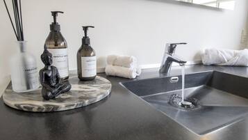 A bathroom counter with hand soap, a hand lotion dispenser, a towel, and a marble tray.