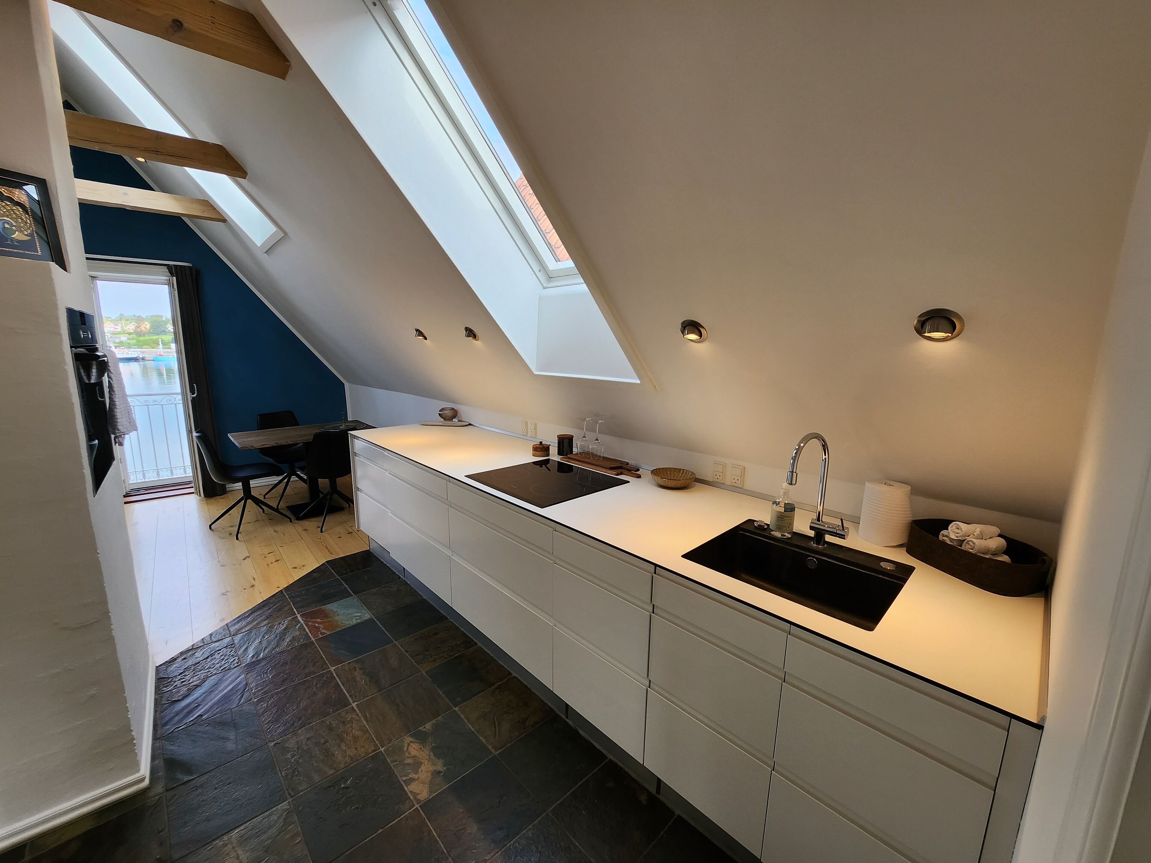 Une cuisine moderne dotée d’une verrière, de deux éviers et d’un coin repas avec une chaise.