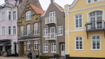 Eine Reihe bunter Gebäude mit unterschiedlichen Baustilen, darunter ein rosafarbenes Gebäude mit Balkon und ein gelbes Gebäude mit weißem Fensterrahmen.