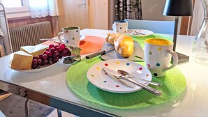 A breakfast table with a croissant, grapes, cheese, and a mug.