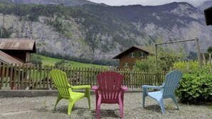A mountain view with a wooden fence and colorful plastic chairs in a garden setting.