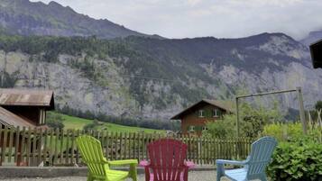 A mountain view with a wooden fence and colorful plastic chairs in a garden setting.