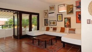 A living room with a sofa, a coffee table, and a dining table. There are framed pictures on the wall. - Villa Amelita is a cozy, breezy & tropical haven (Río Grande)