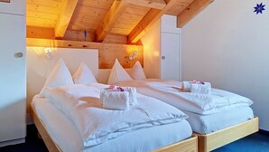 Ein Doppelzimmer mit Holzbalken, einem Bett mit weißer Bettwäsche und einem kleinen dekorativen Gegenstand an der Wand.