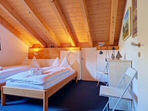 Un dormitorio con techo de madera, una cama, un escritorio y un armario.
