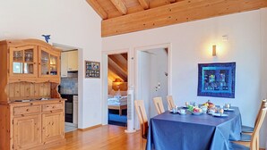 Ein Essbereich mit einem für das Frühstück gedecktem Tisch, Holzschränken und einer Treppe, die zu einem Schlafzimmer auf dem Dach führt.