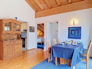Ein Essbereich mit einem für das Frühstück gedecktem Tisch, Holzschränken und einer Treppe, die zu einem Schlafzimmer auf dem Dach führt.