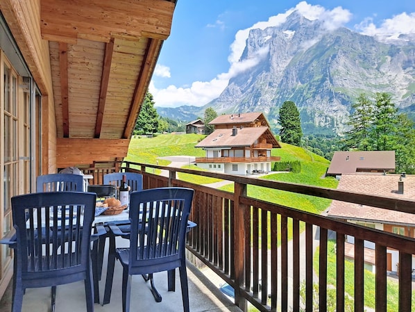 A balcony with wooden railings overlooking a mountainous landscape.