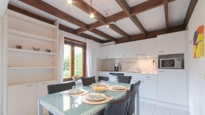 Une cuisine moderne avec des meubles blancs, une table à manger dressée avec des assiettes, des verres et des couverts.