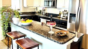 A modern kitchen with white cabinets, a granite countertop, a stainless steel refrigerator, and a built-in microwave. - Eagle’s Roost - Views from the Top! (Banner Elk)