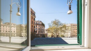 A view from a window with a metal roof, looking out onto a street with buildings and trees.