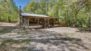 Eine rustikale Holzhütte mit Veranda, umgeben von Bäumen.
