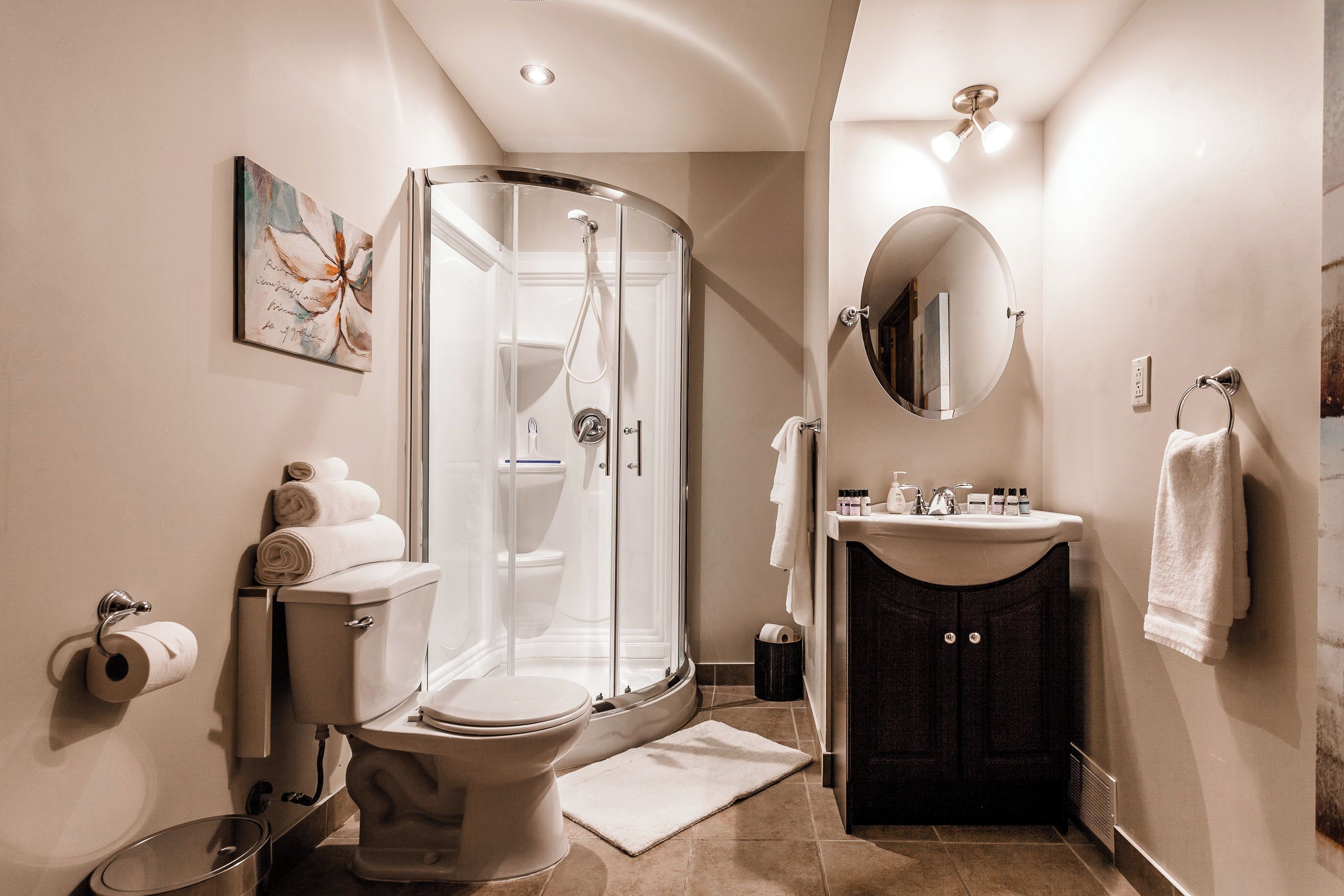 A modern bathroom with a glass-enclosed shower, a toilet, a sink, and a mirror.