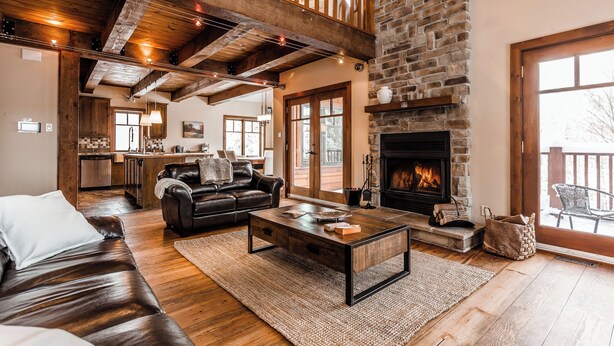 Amplia sala de estar con chimenea, sofá de cuero y piso de madera.