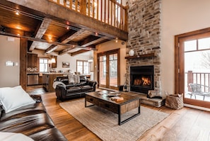 A spacious living area with a fireplace, leather sofa, and wooden flooring.