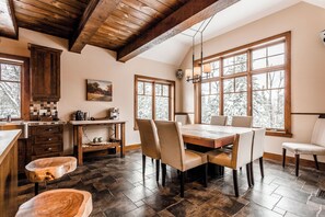 A spacious kitchen with a large dining table, wooden cabinets, and a stone floor.