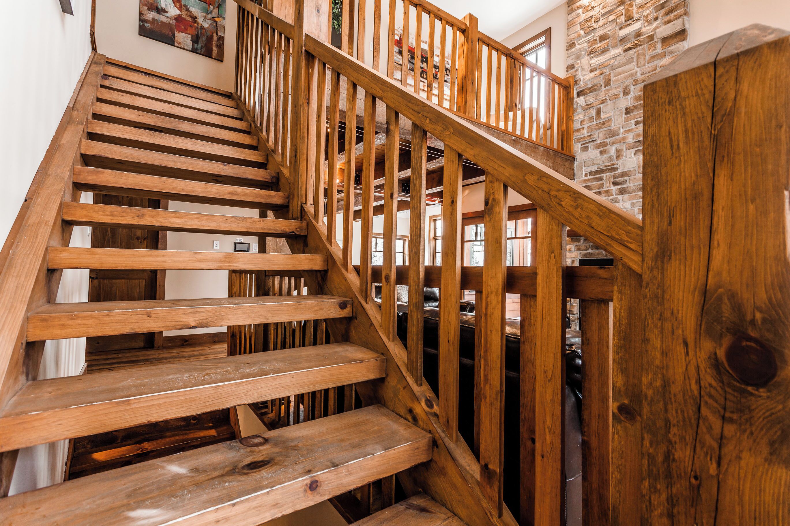 Un escalier en bois, avec un mur en pierre et une rambarde en bois.