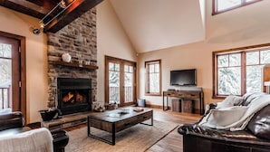 Una sala de estar acogedora con chimenea, muebles de cuero y ventanas amplias.