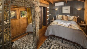 Une chambre confortable avec un grand lit, un mur en pierre et un plafond en bois.