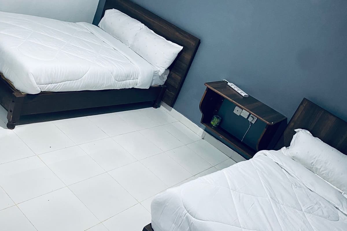 A hotel room with two single beds, a small bedside table, and a nightstand.