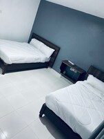 Una habitación de hotel con dos camas individuales, una mesita de noche pequeña y una mesita auxiliar.