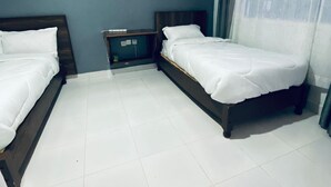 A hotel room with two single beds, a small bedside table, and a window with curtains. - Dad's Place (Karatina)